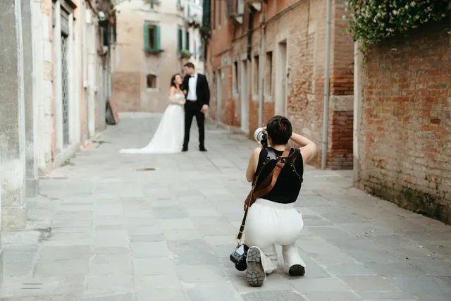 Fotógrafa haciendo fotos a unos novios en una calle