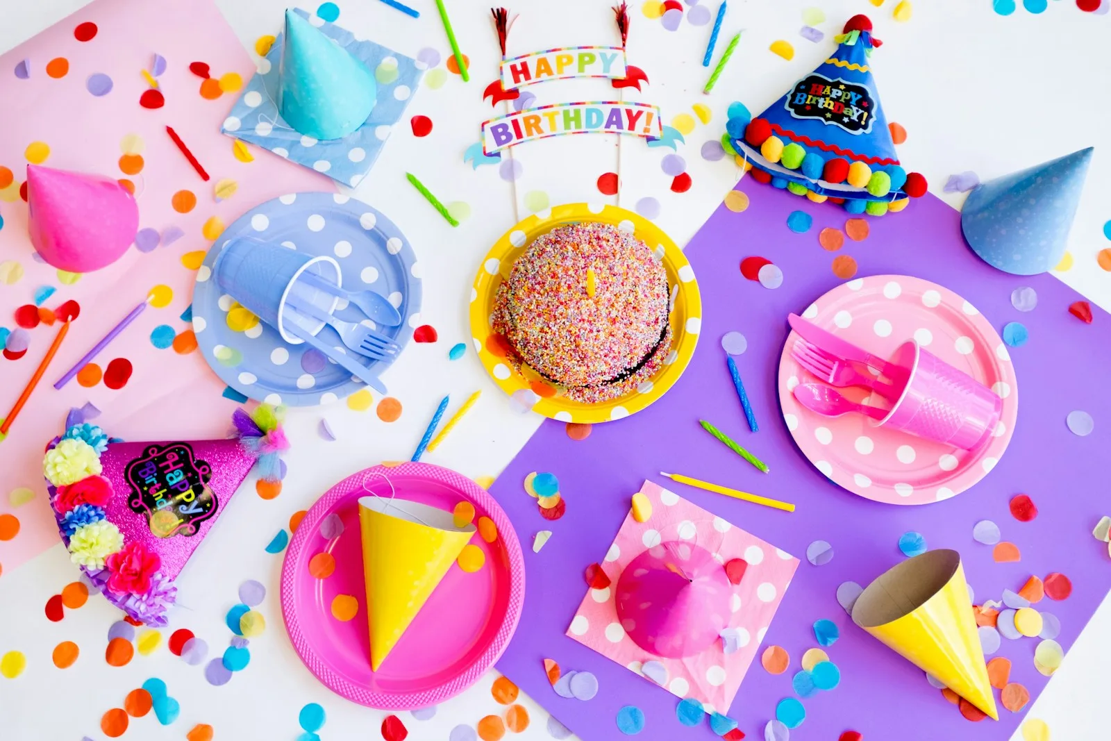 Decoración de cumpleaños con gorros de fiesta, platos de colores y confeti